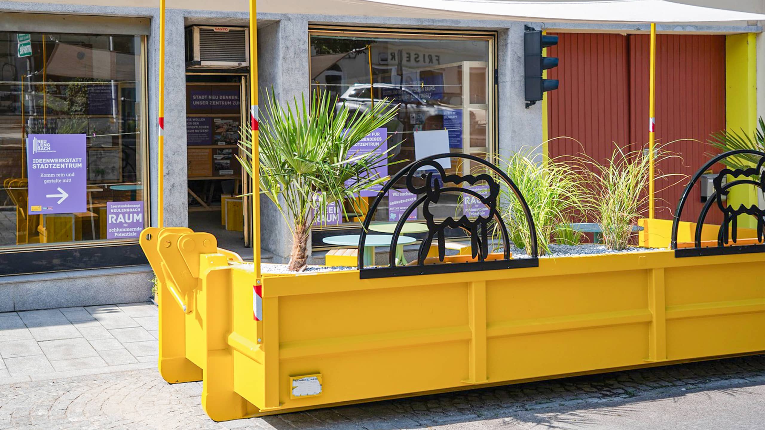 Gelbes Parklet mit Sitzgelegenheiten und Begrünung vor der Ideenwerkstatt in Neulengbach – ein Impulsprojekt zur aktiven Leerstandsaktivierung im Stadtraum.