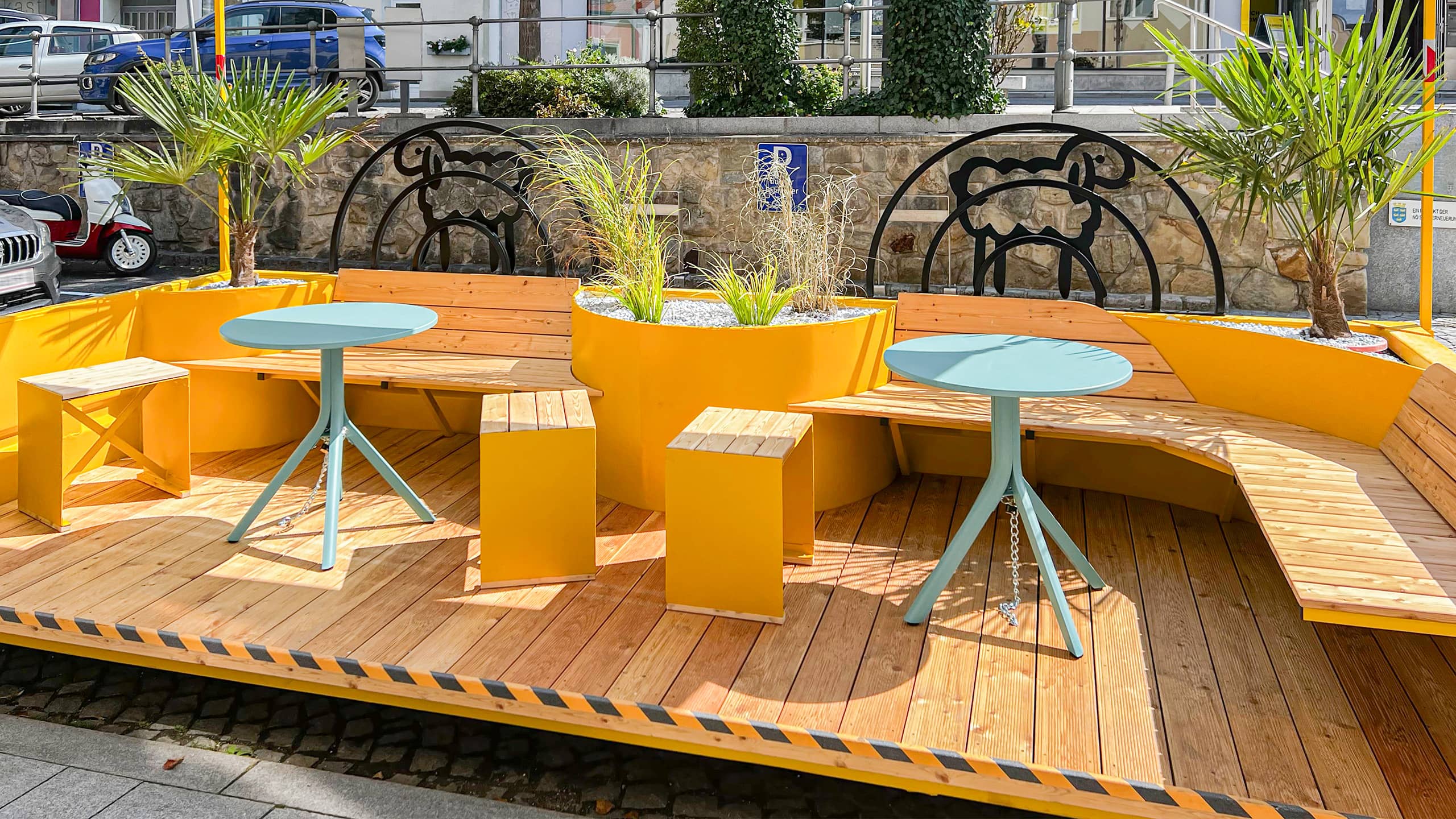 Modern gestaltetes Parklet mit gelben Holzmodulen, Begrünung und Stadtmobiliar – innovatives Element im Rahmen der Leerstandsaktivierung Neulengbach.
