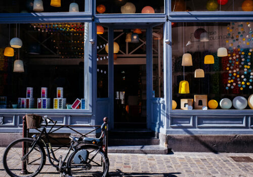 Schaufenster eines leerstehenden oder neu belebten Geschäfts mit bunter Dekoration und Fahrrad im Vordergrund – Symbolbild für erfolgreiche Leerstandsaktivierung durch kreative Zwischennutzung und gezieltes Standortmarketing.