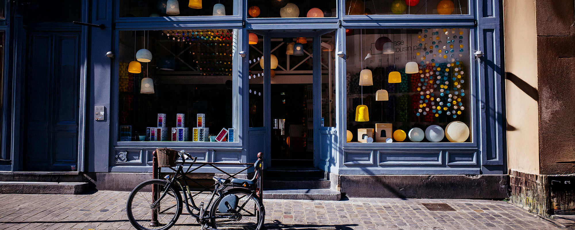 Schaufenster eines leerstehenden oder neu belebten Geschäfts mit bunter Dekoration und Fahrrad im Vordergrund – Symbolbild für erfolgreiche Leerstandsaktivierung durch kreative Zwischennutzung und gezieltes Standortmarketing.