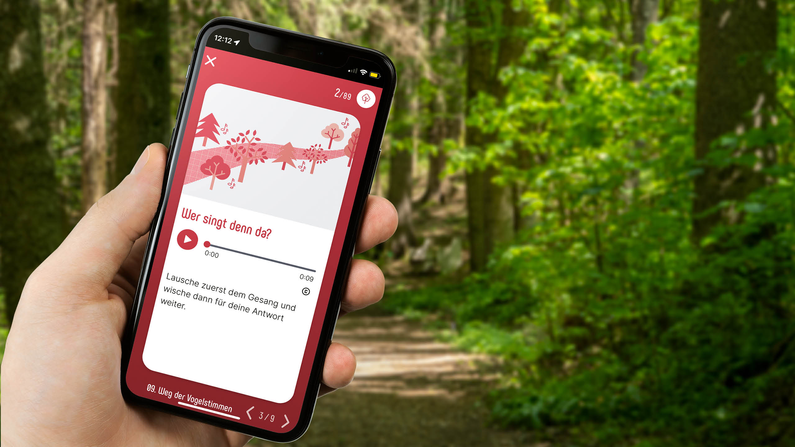Hand hält Smartphone mit geöffneter App und Quizfrage zu Vogelstimmen auf dem KlimaWaldWeg Hainfeld.