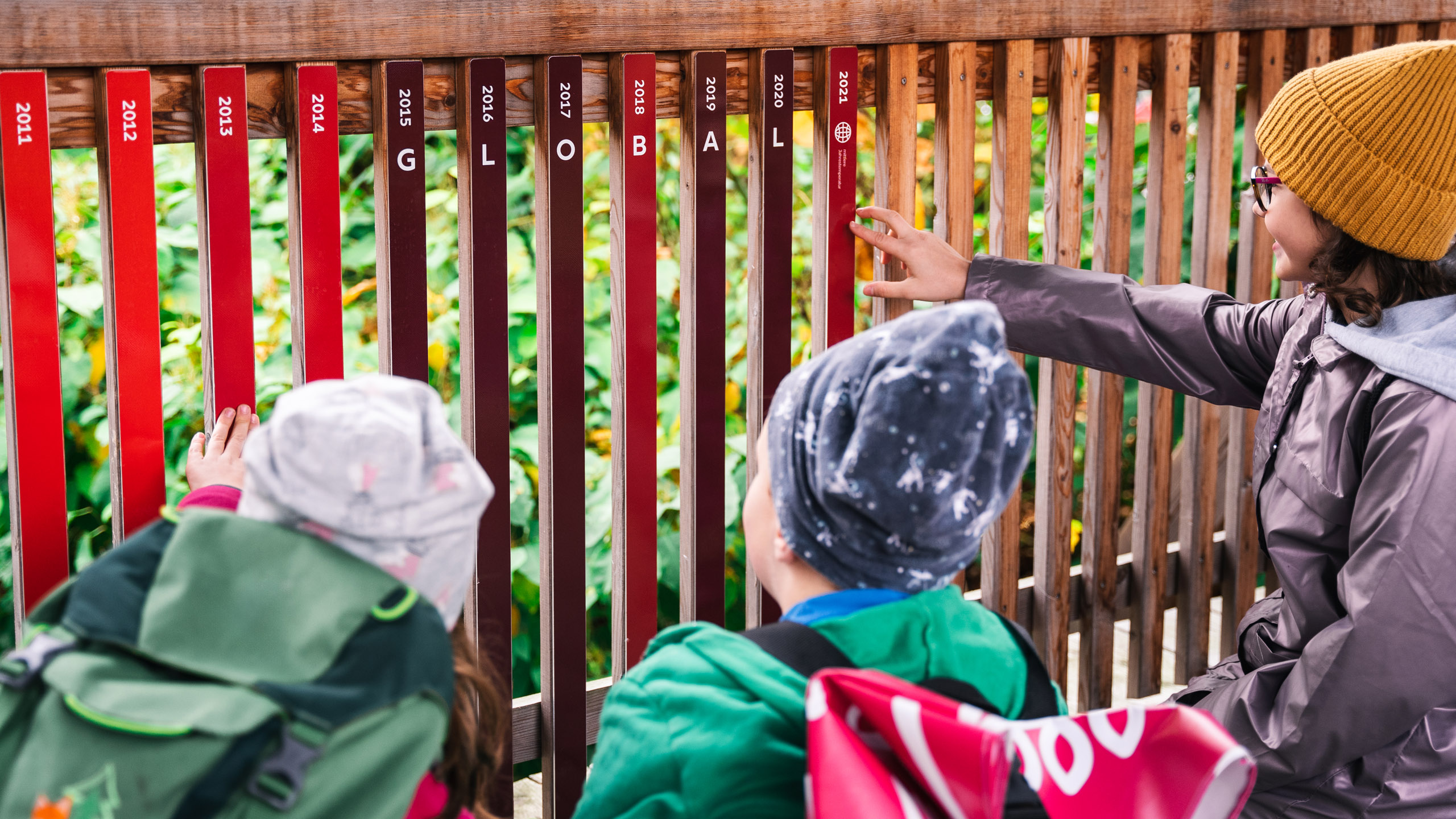 Kinder betrachten farbige Holzlatten mit Jahreszahlen, die die globale Temperaturentwicklung visualisieren.