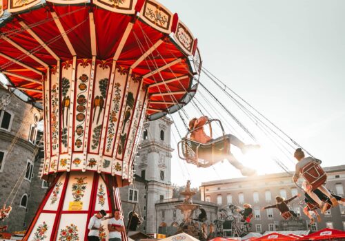 Stimmungsvolle Szene auf einem historischen Stadtplatz mit nostalgischem Kettenkarussell und fröhlichen Besucher*innen – ein lebendiges Beispiel für emotionale Inszenierung der Stadt als Marke.
