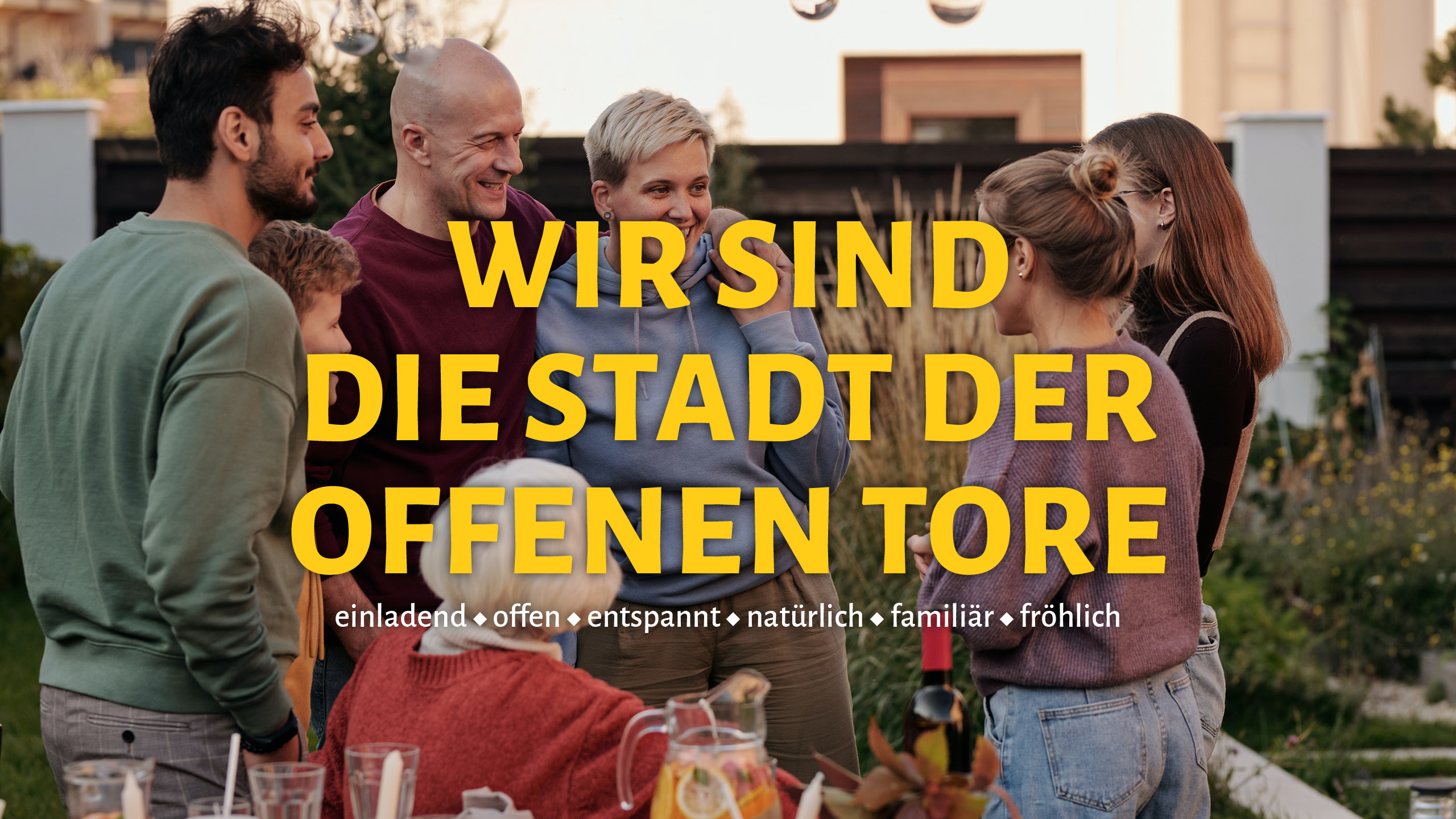 Menschen beim Gartenfest in Groß-Enzersdorf mit Schriftzug „Wir sind die Stadt der offenen Tore“ – Ausdruck von Gemeinschaft und Lebensfreude.