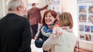 Teilnehmer:innen des Stadtmarken-Workshops im Gespräch, lächelnde Frau im Mittelpunkt der Szene.