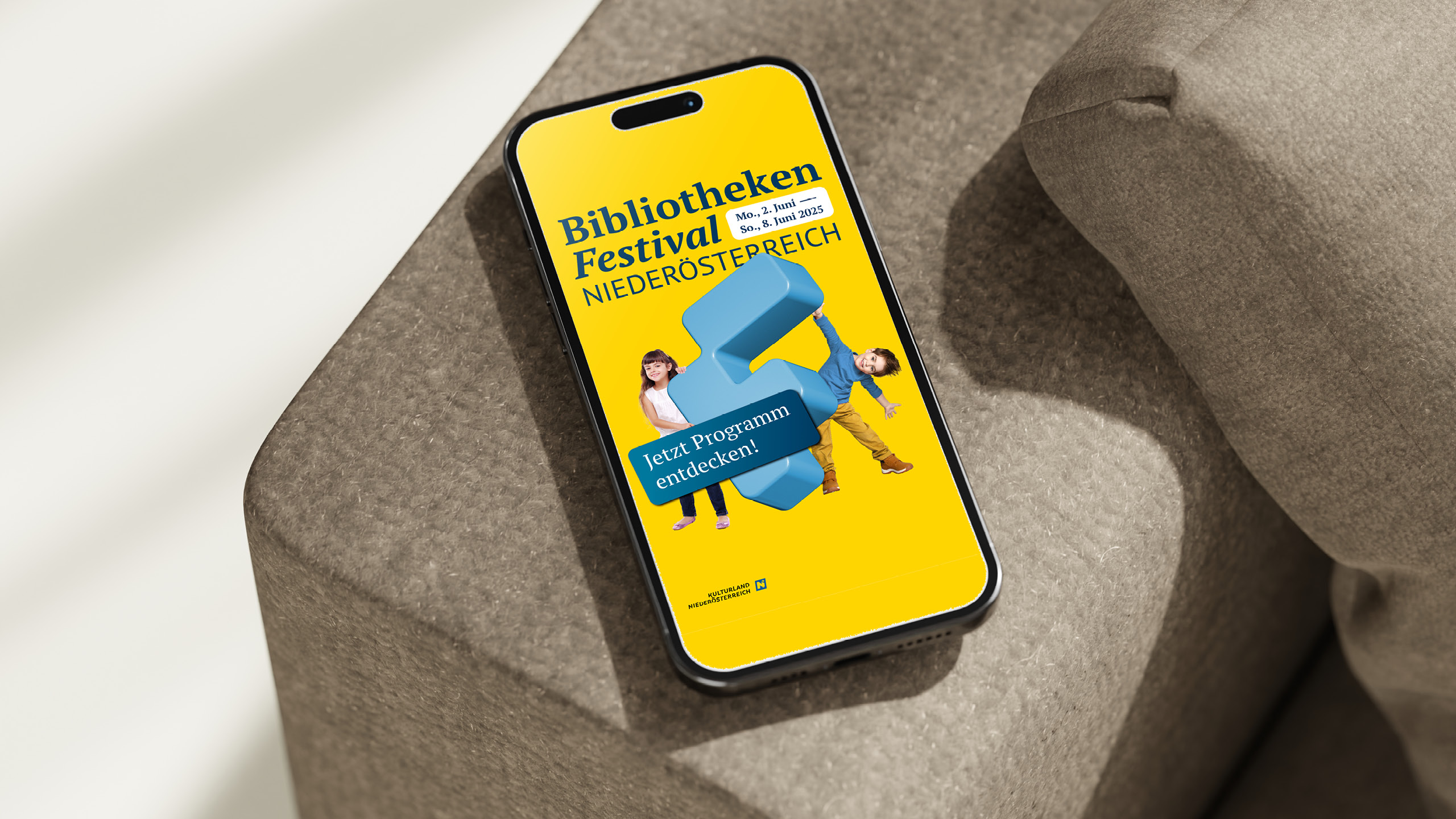 martphone mit Festivalprogramm des Bibliotheken-Festivals Niederösterreich 2025 – gelber Hintergrund, zentrales F-Motiv, Hinweis auf Online-Entdeckung.