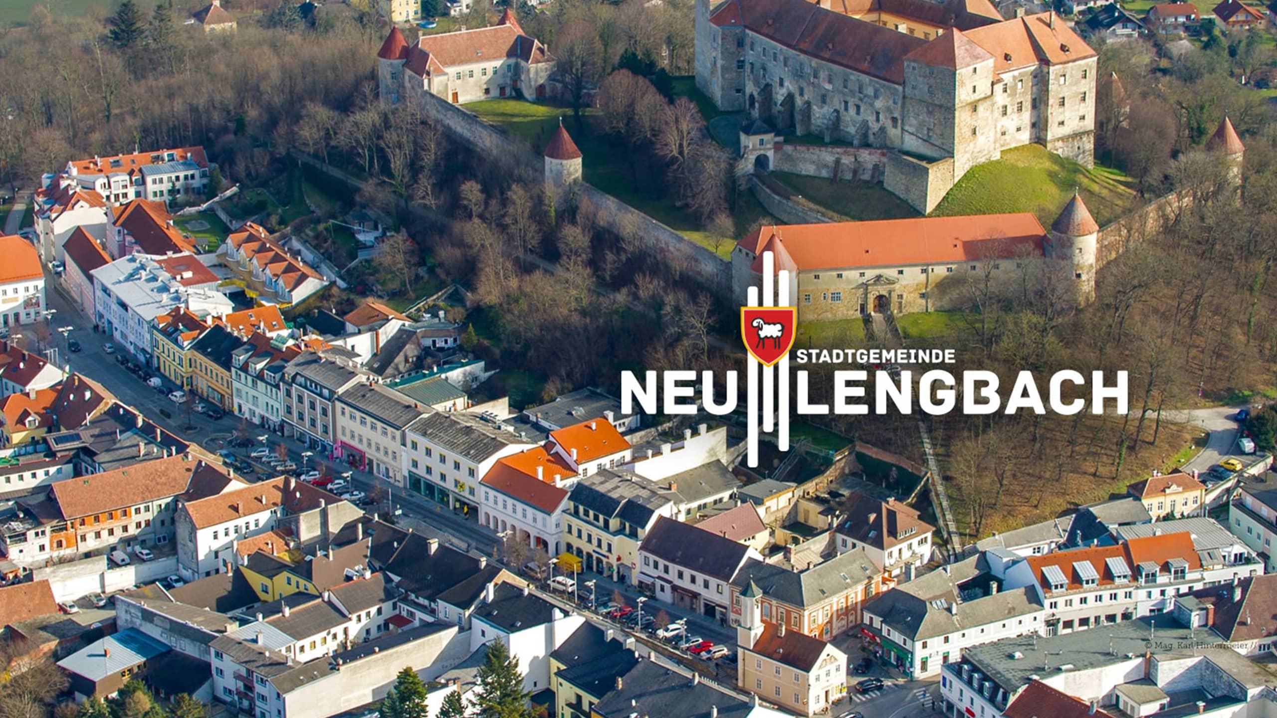 Luftbild von Neulengbach mit Stadtlogo und Burganlage – starke Stadtmarke für eine traditionsreiche Stadtgemeinde mit historischem Zentrum.