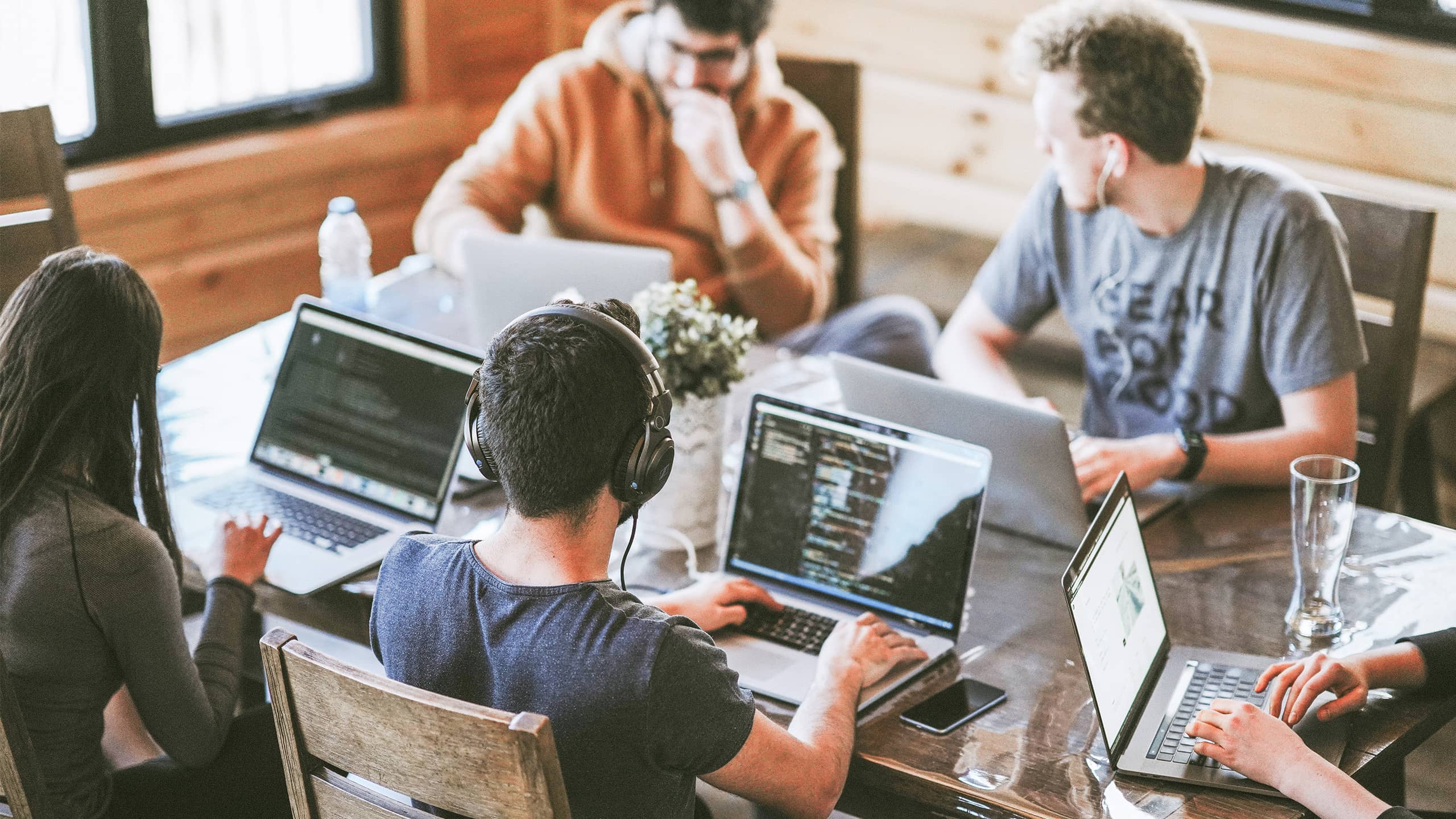 Junges Team arbeitet an Laptops in kreativem Workspace. Symbolbild für innovative Gründungskultur von Startup-Citys.