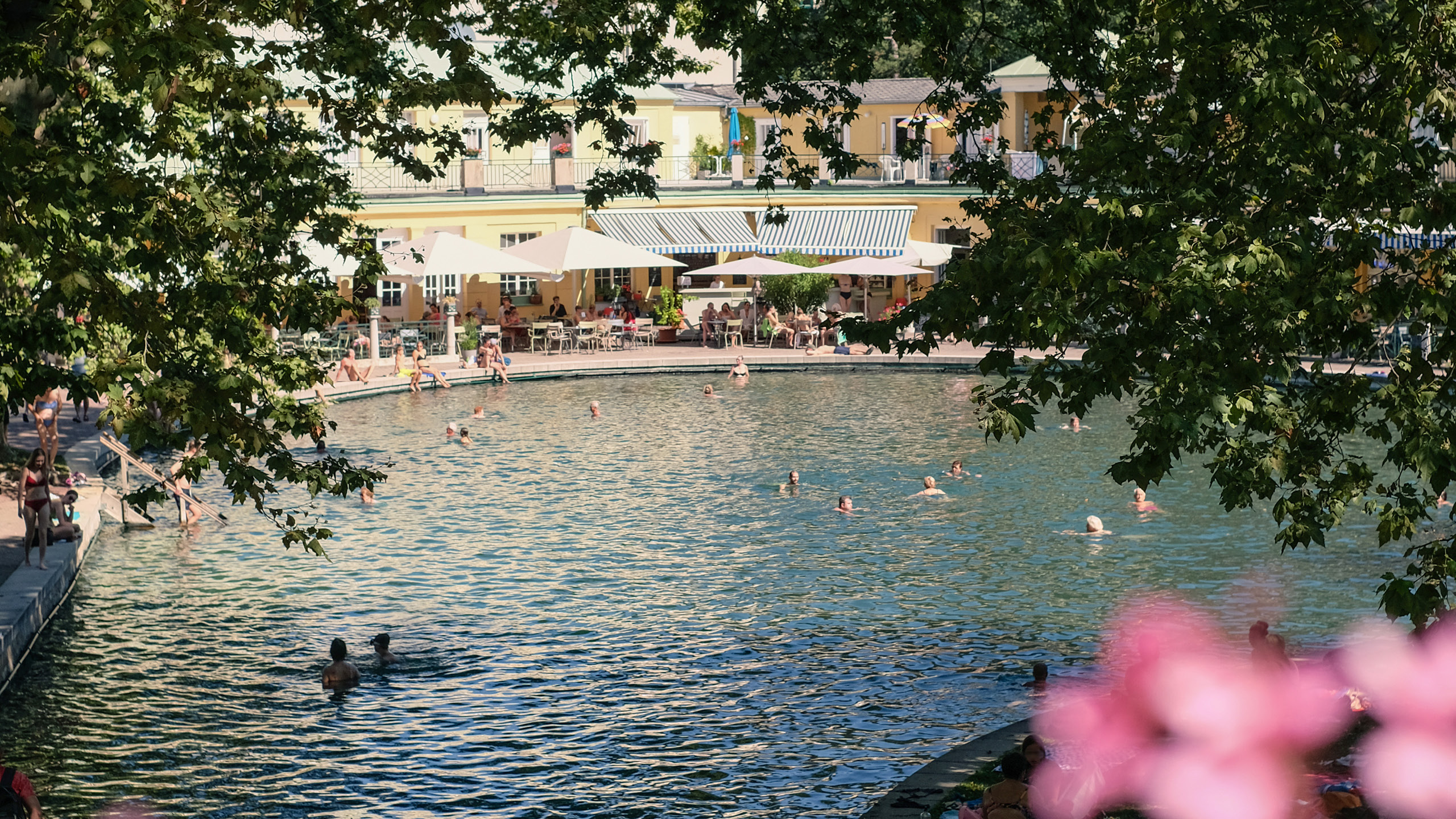 Blick auf das Thermalbad von Bad Vöslau mit Badegästen, umgeben von Natur und historischen Gebäuden – authentische Bildwelt.